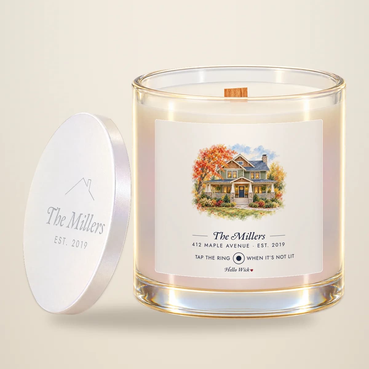A Hello Wick candle labelled The Millers, with a watercolour of their house, its lid leaning beside it